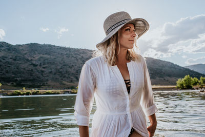 Woman in a dress standing in water looking away on a sunny day