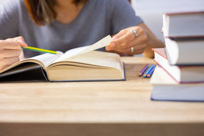 Midsection of woman reading book on table