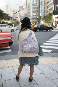 Rear view of woman walking on footpath in city