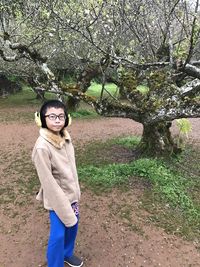 Portrait of young woman standing by tree