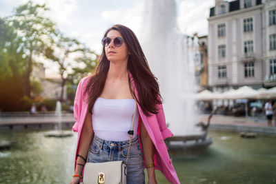 Young woman wearing sunglasses standing by canal