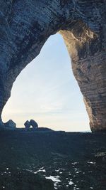 Rock formation at beach against sky during sunset