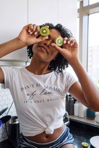 Beautiful black woman with curly hair holding kiwis in her hands
