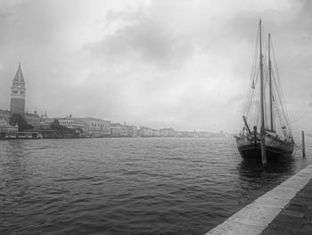 Sailboats sailing in sea against cloudy sky