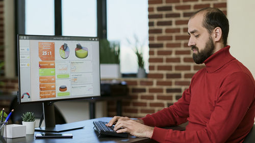 Young businessman using desktop pc at desk