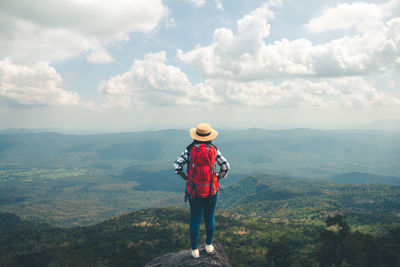 Rear view of man standing on mountain against sky