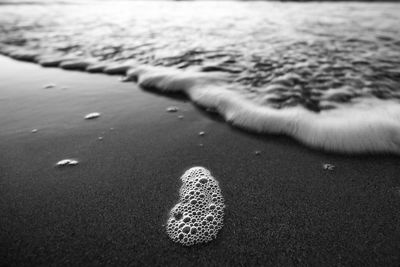 Close-up of footprints foam on sand at beach