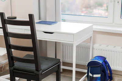 Student's workplace at home. white desk and black chair near the window.