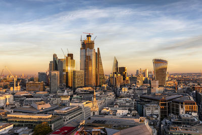 Aerial view of buildings in city against cloudy sky