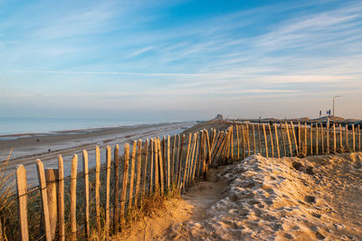 Wooden posts on beach against sky