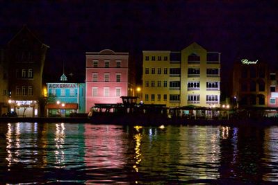 Illuminated buildings by river at night