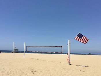 Lifeguard hut on beach against clear blue sky with american flag