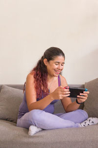 Young woman using mobile phone while sitting on sofa at home