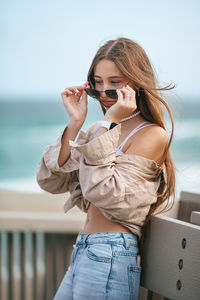 Side view of young woman drinking wine at beach