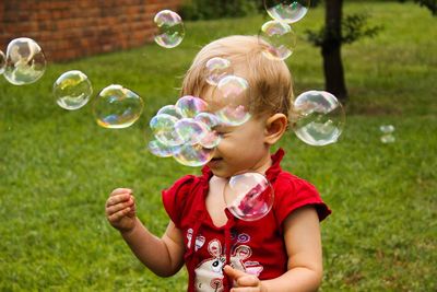 Baby girl playing with bubbles in lawn