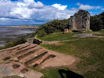 Old ruin building by sea against cloudy sky