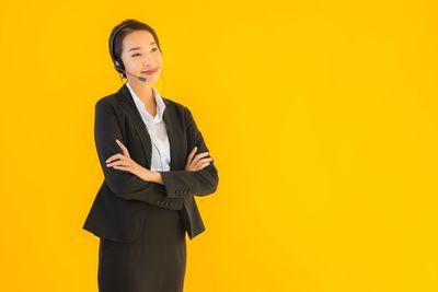 Portrait of a smiling young woman against yellow background