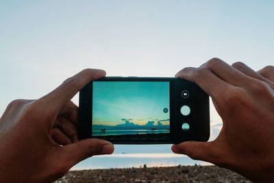 Midsection of person using mobile phone against sky