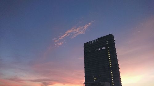 Low angle view of illuminated building against sky at sunset