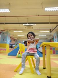 Full length portrait of girl standing against illuminated ceiling