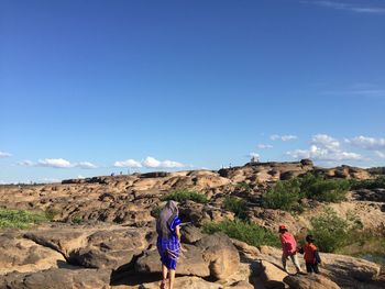 People standing on rocky mountains against sky