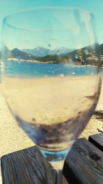 Close-up of beer glass at beach against sky