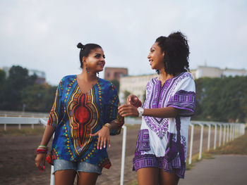 Young women standing on shore against sky