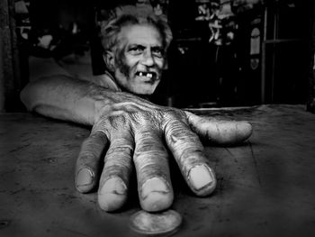 Portrait of smiling man holding coin at table