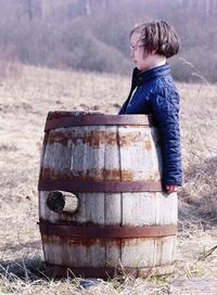 Side view of boy looking away in barrel on grass
