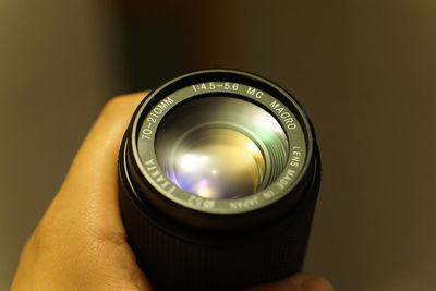 Cropped image of hand holding digital camera lens