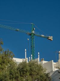 Low angle view of crane against blue sky