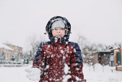 Close up outdoor winter portrait of boy playing snowballs. authentic, real, candid portrait of cute