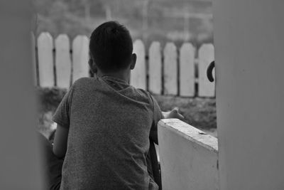 Rear view of boy standing against wall