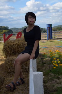 Woman sitting on railing at farm