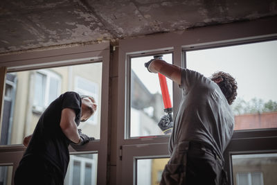 Two people seal cracks with silicone on a window frame. person