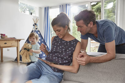 Couple using tablet at home with boy in background