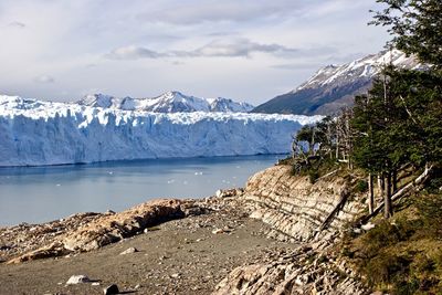 Scenic view of glaciers and snowcapped mountains against cloudy sky