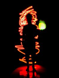 Silhouette man standing against illuminated lights at night