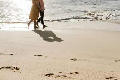 Low section of couple walking at beach