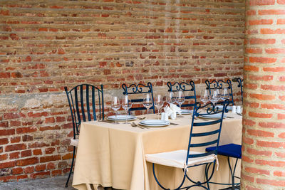 Empty chairs and table against brick wall