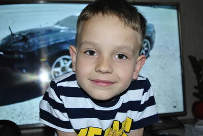 Portrait of cute boy sitting against television set at home