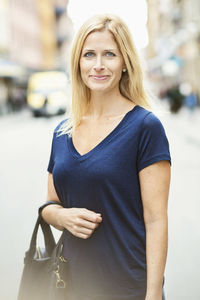 Portrait of smiling mid adult woman standing on street in city