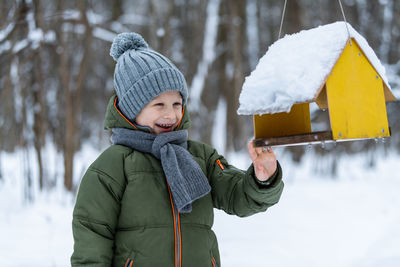 Boy touching bird feeder during winter