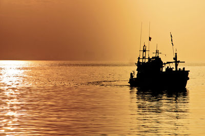 Silhouette ship in sea against sky during sunset