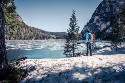 Rear view full length of man standing by lake during winter