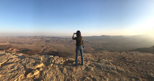 Man standing on rock against sky