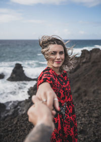 Portrait of smiling young woman on beach against sky