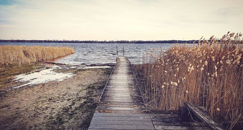 View of boardwalk over sea against sky