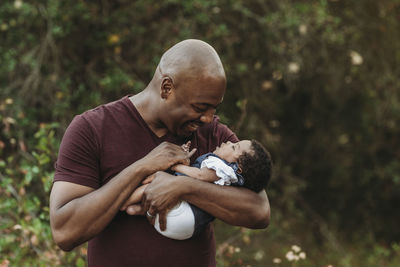 Close up happy father holding and smiling at newborn girl outside