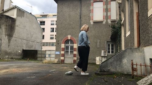 Rear view of woman walking by buildings in city